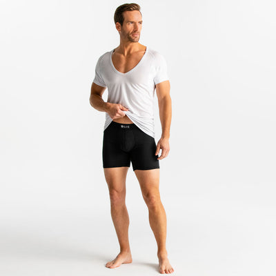 Man wearing a white Ejis deep v micro modal undershirt and black underwear on a plain background