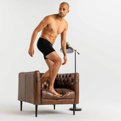 man wearing black Ejis essential boxer briefs standing on leather chair