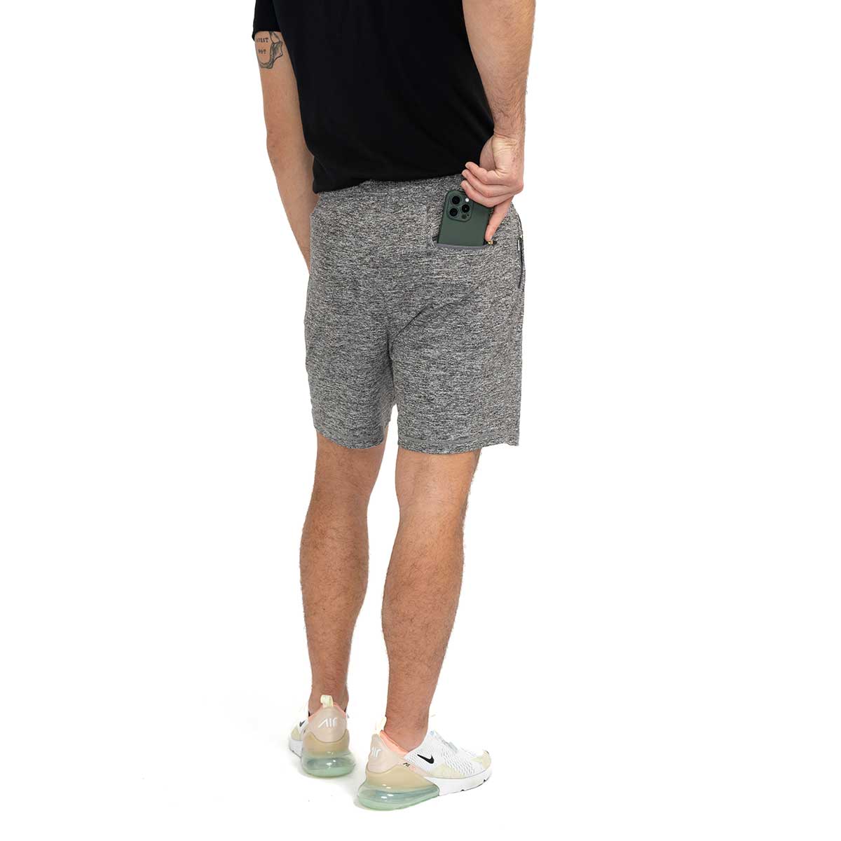 back view of person wearing Ejis Conquest athletic shorts and black tshirt, placing cell phone in back pocket