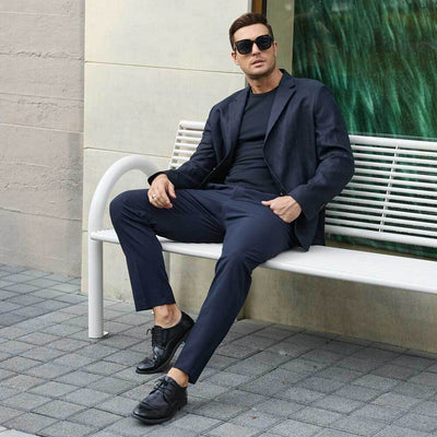 Man wearing a navy suit with a black Ejis TotalShield sweat proof t-shirt sitting on a bench, wearing sunglasses.