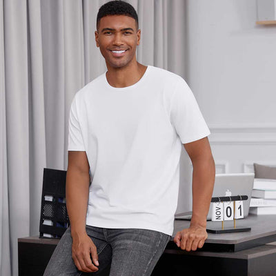 man wearing white TotalShield t-shirt and jeans leaning against a desk