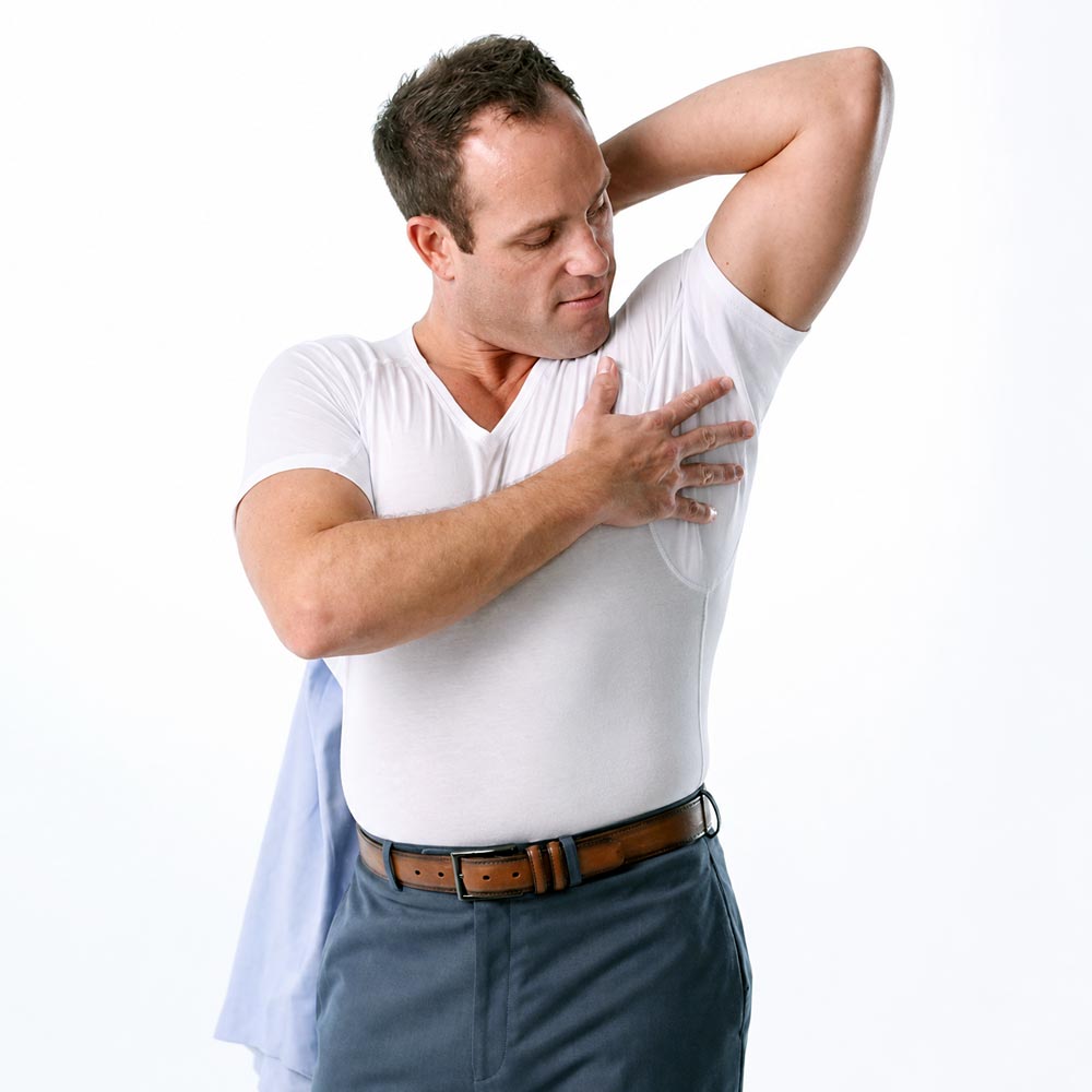 Man wearing a white Ejis cotton undershirt  and blue pants, holding his hand over the protective underarm pad