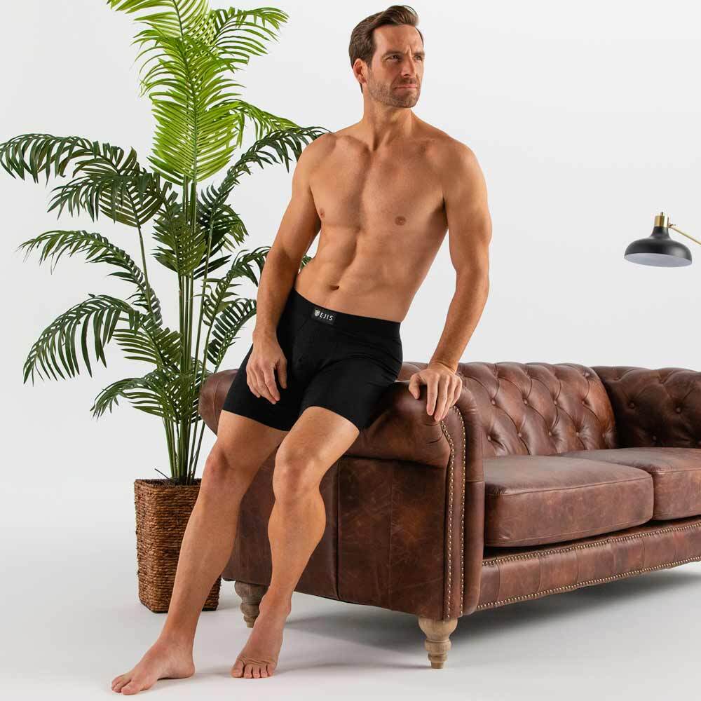 man wearing black Ejis essential boxer briefs leaning against sofa