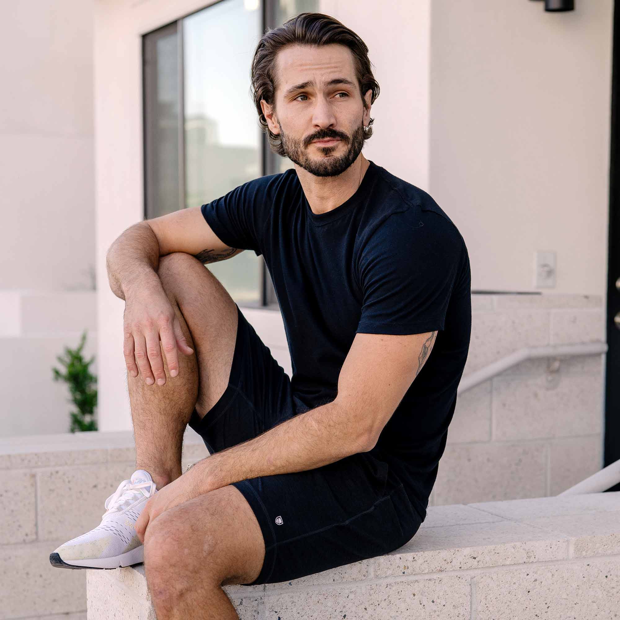 man sitting outside wearing black Ejis Conquest athletic shorts and black tshirt