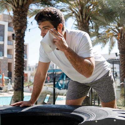 man wiping sweating face with Ejis handkerchief in outdoor workout area