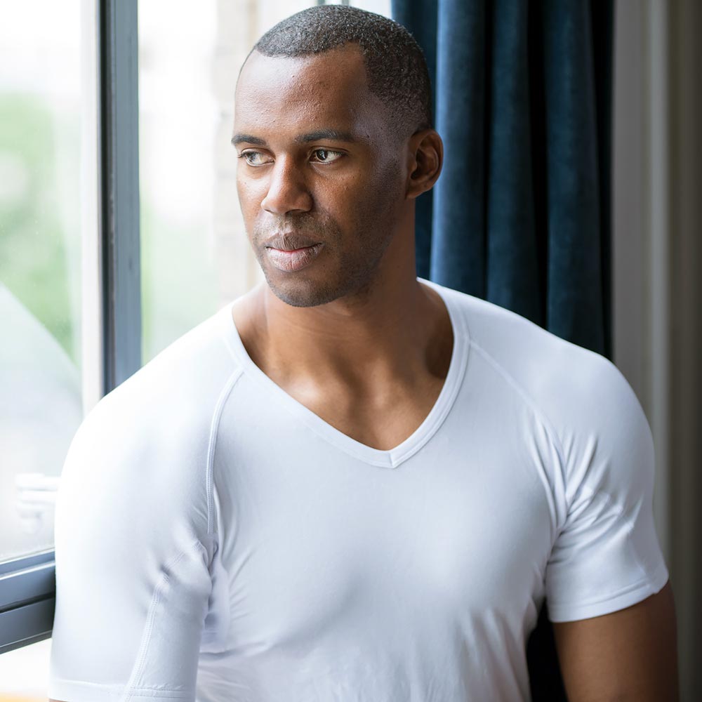Man wearing a white Ejis v-neck micro modal sweat proof undeshirt sitting by a window