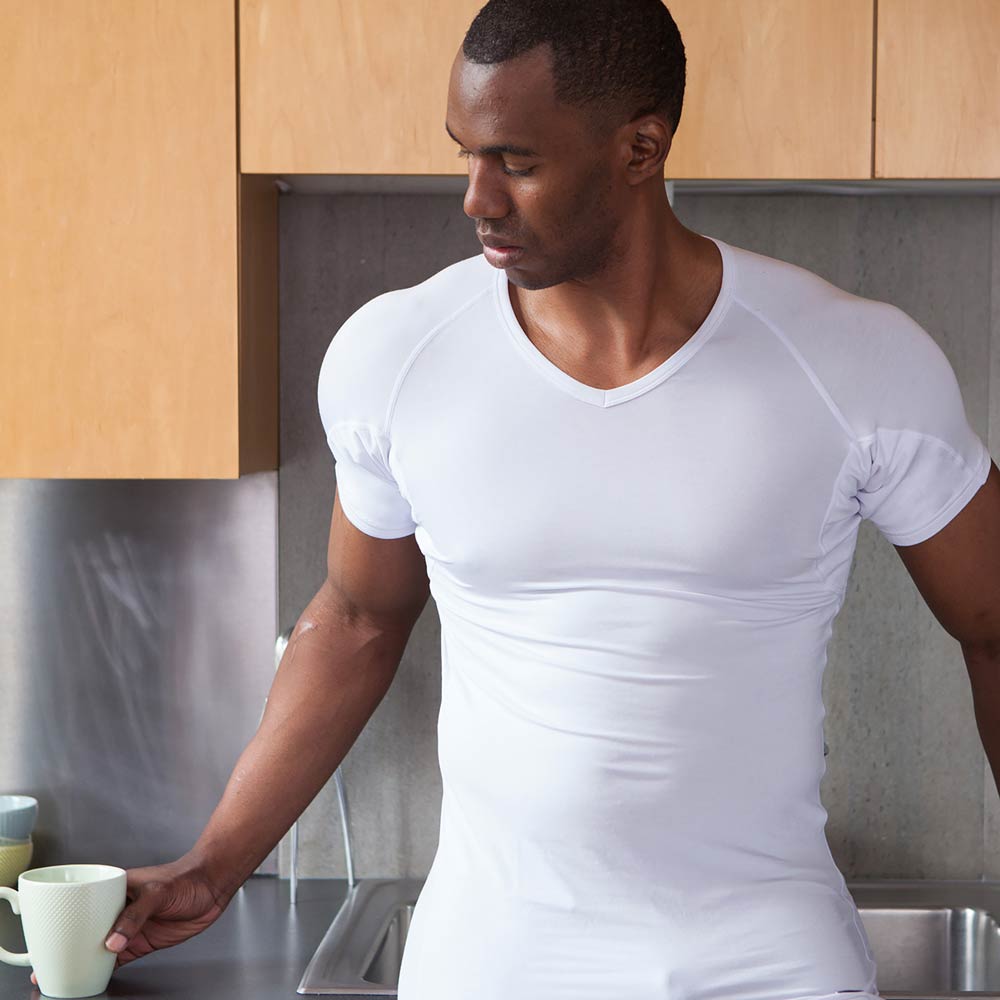 man wearing white Ejis v-neck micro modal sweat proof undershirt holding a mug in a kitchen setting